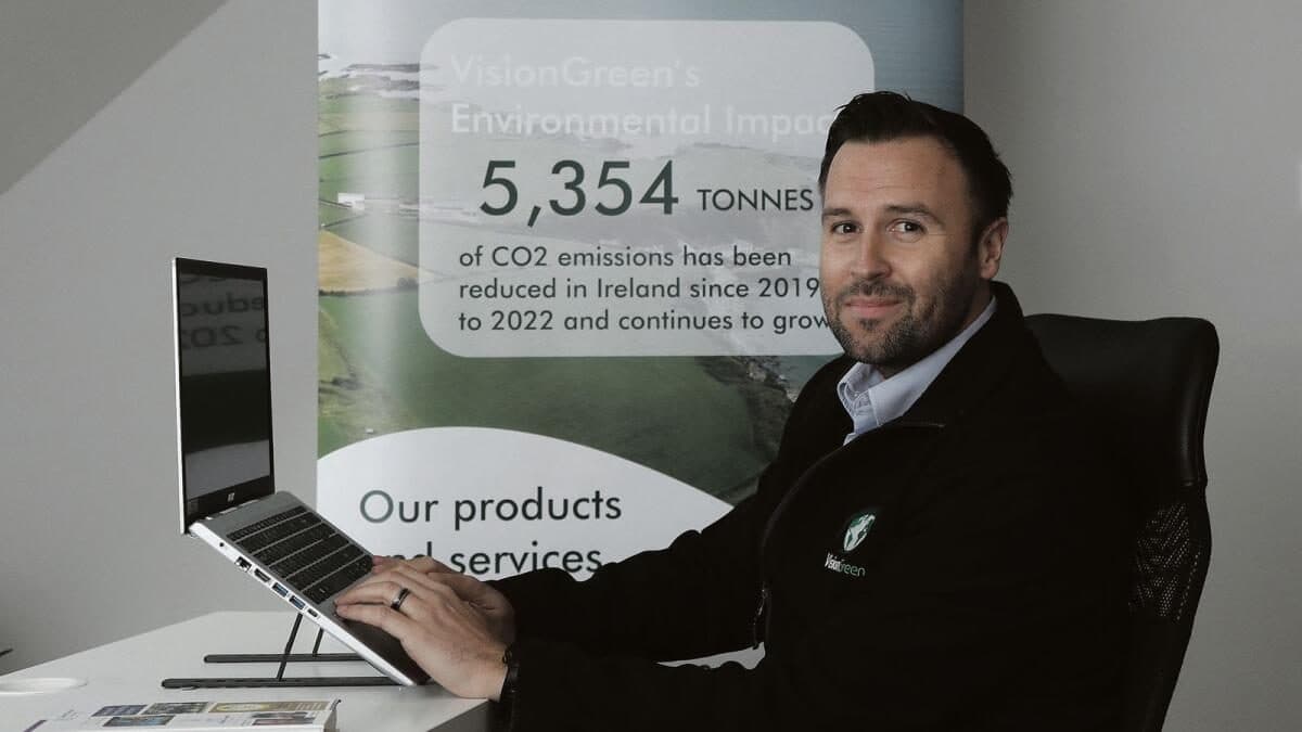 A member of the VisionGreen team at his desk, in front of a VisionGreen display stand.